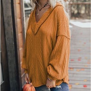 Meritt burnt orange vneck sweater w/exposed black stitching at neck & shoulders